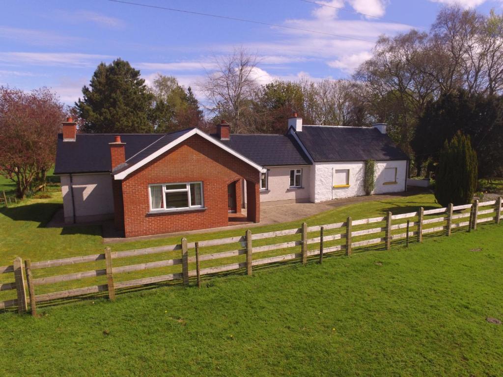 ein Haus mit einem Zaun davor in der Unterkunft Lough Shore Cottage in Magherafelt