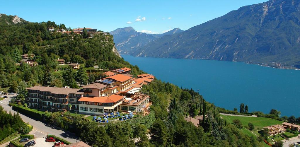 ein Gebäude auf einem Hügel neben einem Wasserkörper in der Unterkunft Hotel Pineta Campi in Tremosine sul Garda