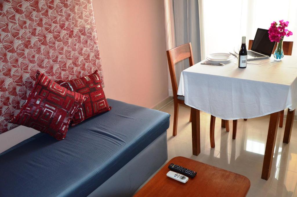 Résidence Bertille Abidjan Cocody في أبيدجان: غرفة معيشة مع أريكة زرقاء وطاولة مع طاولة