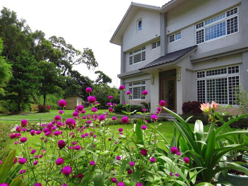 una casa con flores rosas delante de un patio en Fanny Manor B&B, en Emei