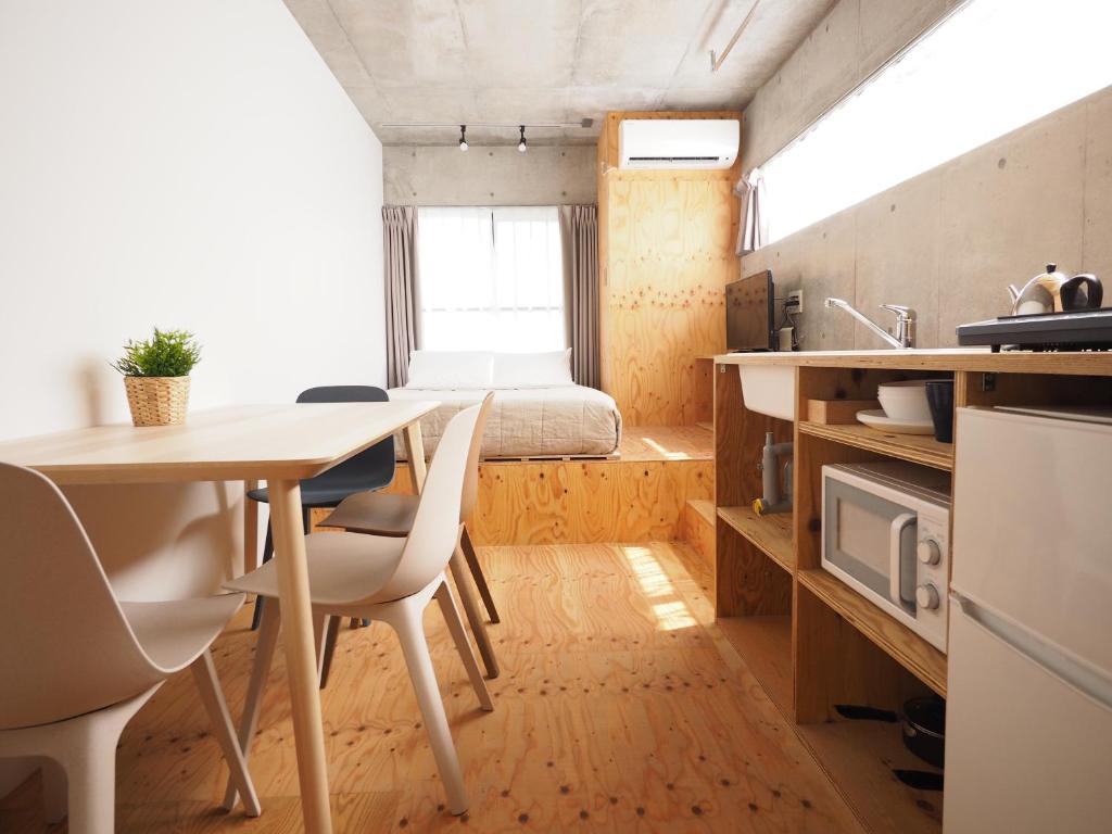 東京にあるスマイルステイ押上のテーブルとベッドが備わる小さなアパートメントです。
