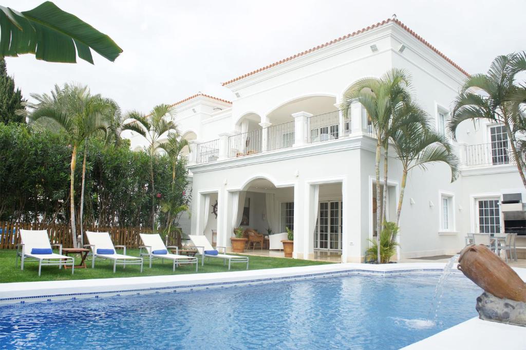 a white house with a swimming pool and palm trees at Villas Espléndida in Adeje