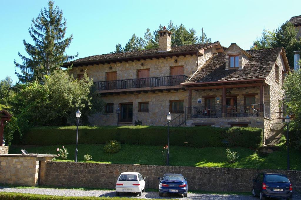 una casa con dos coches estacionados frente a ella en Hosteleria Santa Cruz en Santa Cruz de la Serós