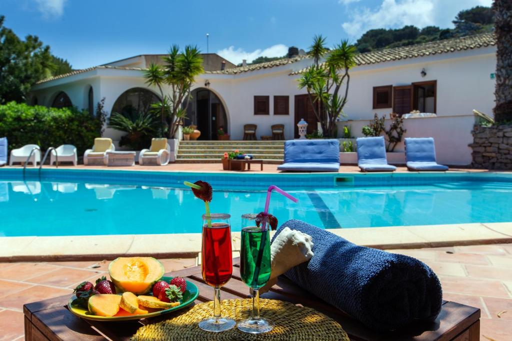 a person laying on a table with a plate of fruit and drinks at Relais Le Nereidi in San Vito lo Capo