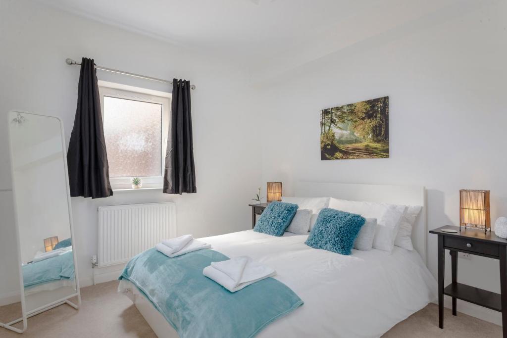 1 dormitorio con cama blanca y almohadas azules en 1 Bed Apt Sleeps 4, en Luton