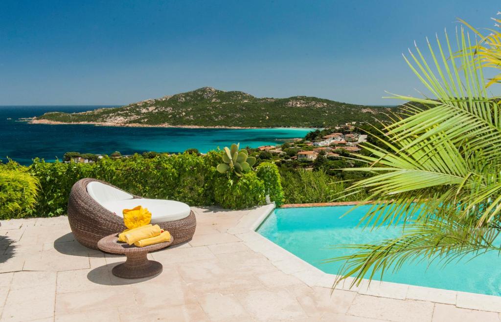 a resort with a pool and a chair with a cat on it at Villa Anna in Porto Cervo