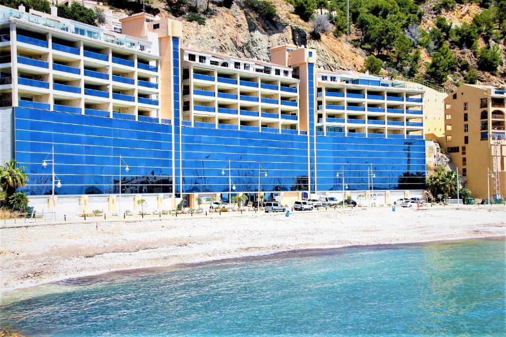 ein blaues Gebäude am Strand neben dem Wasser in der Unterkunft 1st Line Mascarat Beach - Solarium Terrace & Pool in Altea