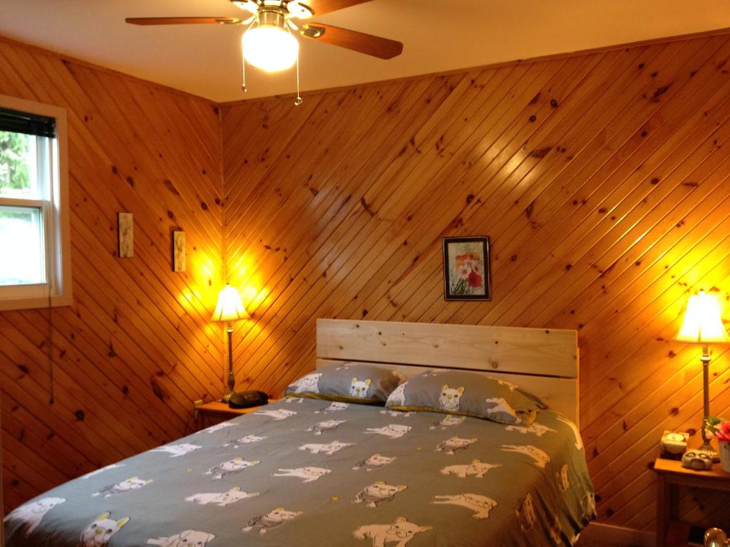 1 dormitorio con 1 cama en una pared de madera en Bubbling Brook Cottages en Cavendish
