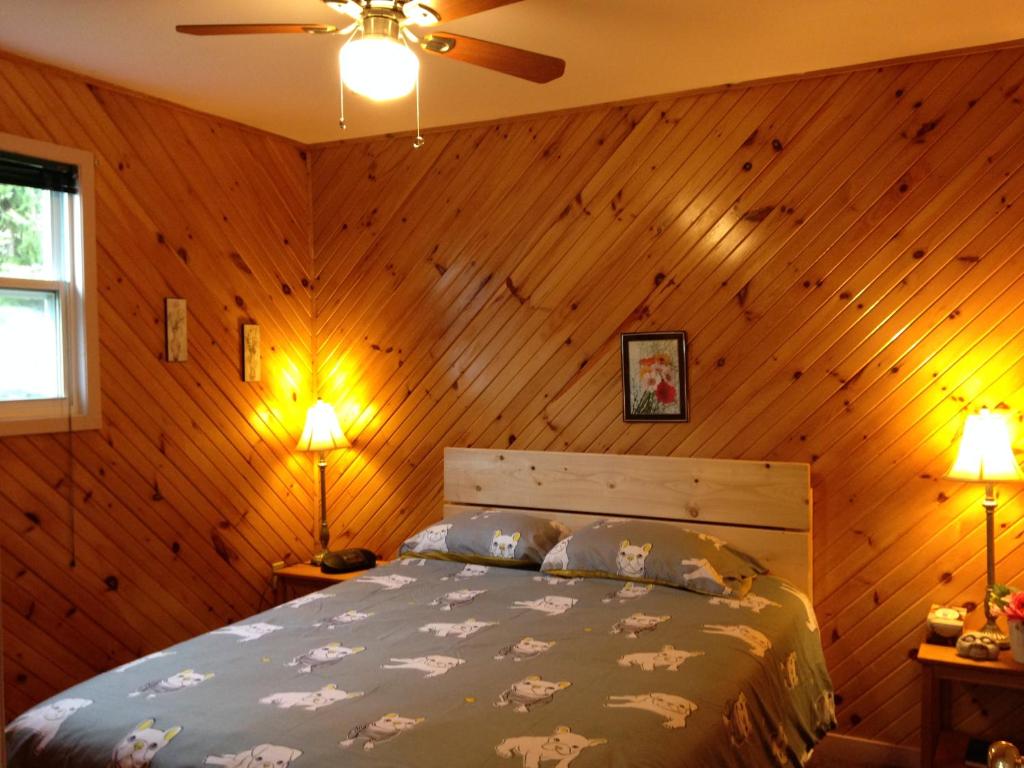 - une chambre avec un lit dans un mur en bois dans l'établissement Bubbling Brook Cottages, à Cavendish