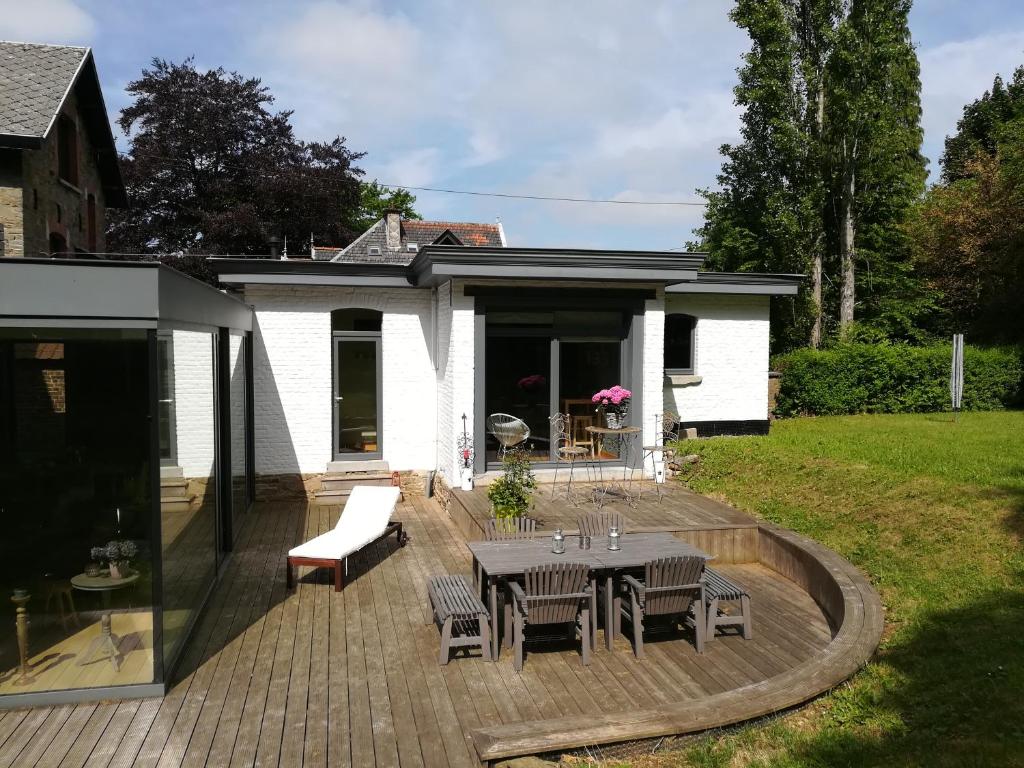 een patio met een tafel en stoelen en een huis bij La Suite Des Pervenches in Spa