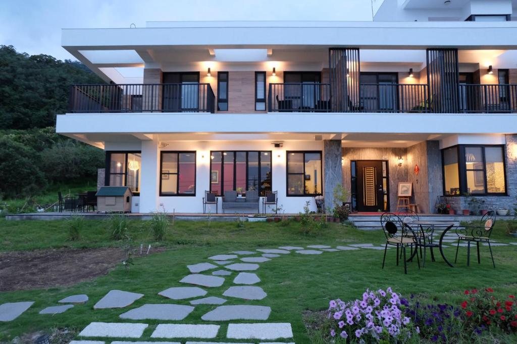 a large white house with a patio and a yard at Moonlit Seaview Homestay in Donghe
