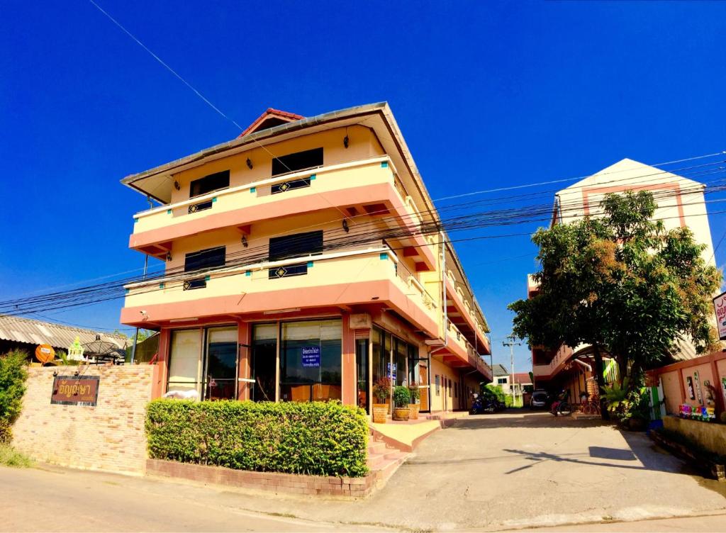 a tall yellow building with windows on a street at Anchisa Mansion in Phayao