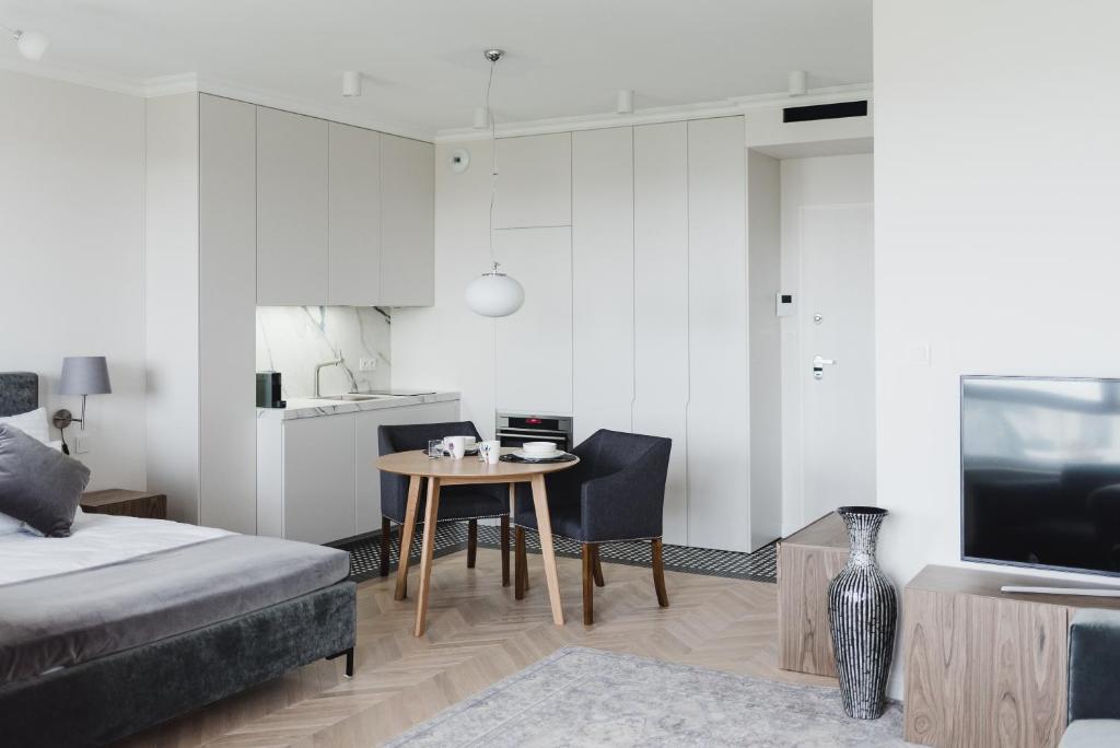 a living room with a bed and a table and a kitchen at LuxLux Apartments Metro Slodowiec in Warsaw