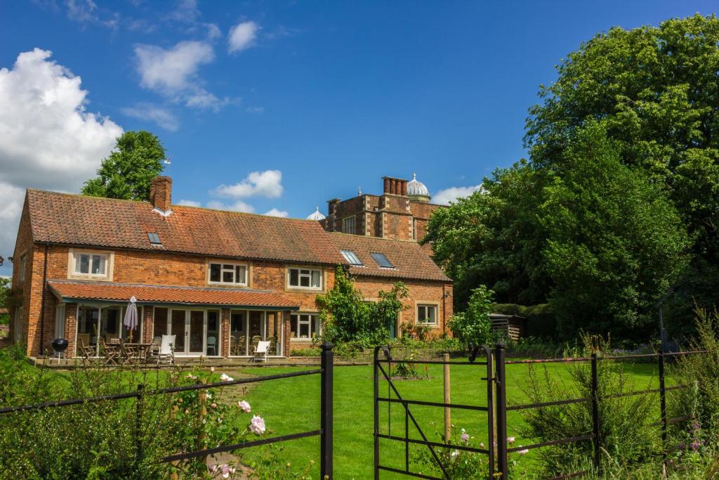 an old brick house with a fence in front of it at The Brewhouse in Doddington