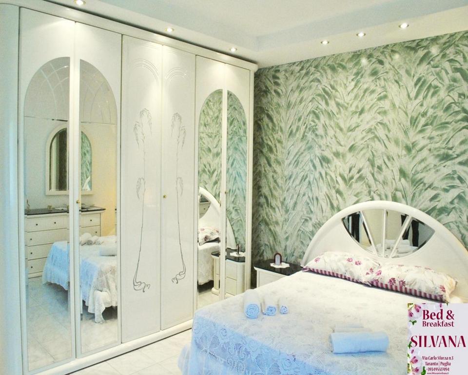 sypialnia z białym łóżkiem i dużym lustrem w obiekcie Bed and Breakfast Silvana w mieście Tarent