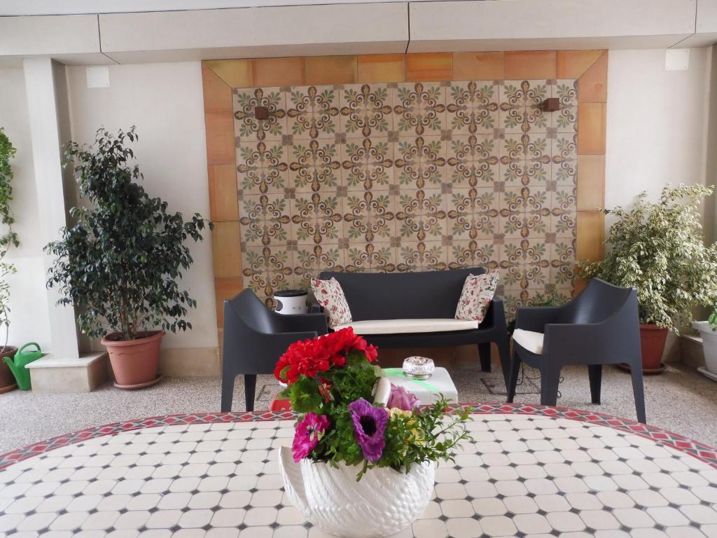 un vestíbulo con mesa, sillas y flores en Maiolica guest house,a delicious studio, en Siracusa