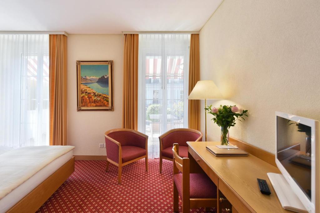 um quarto de hotel com uma cama, uma escrivaninha e uma televisão em Elite em Lausana