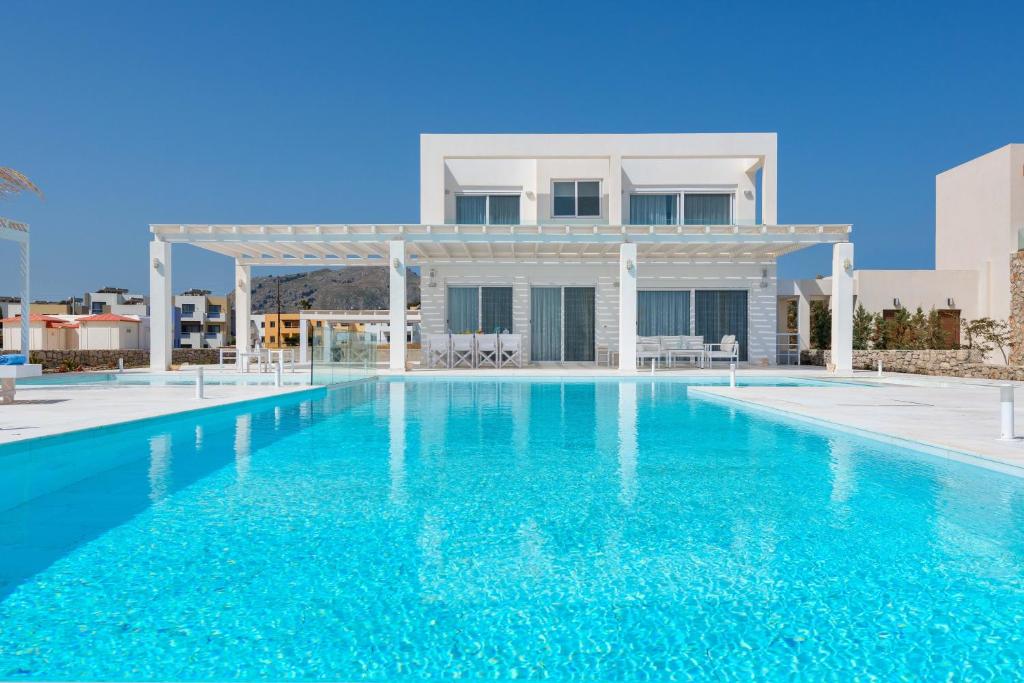 a villa with a swimming pool in front of a house at Maria & Nada Beachfront Villas in Kolimbia