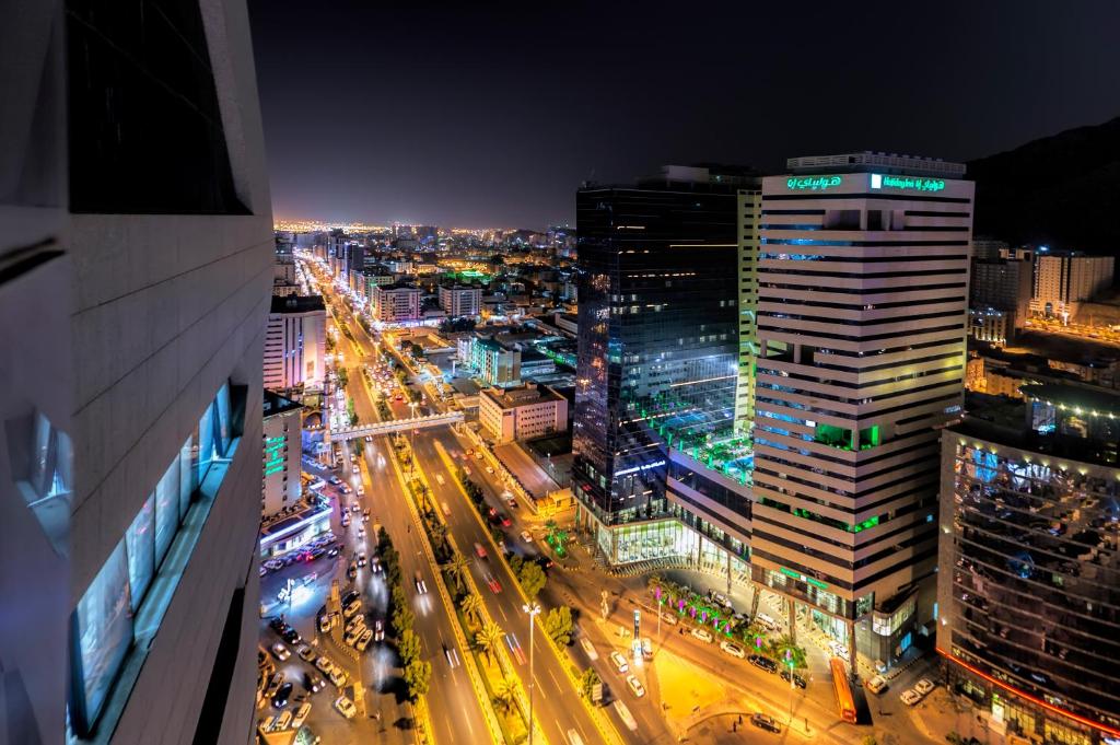 uma cidade iluminada à noite com trânsito em Holiday Suites Al Azizia em Meca