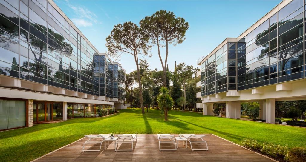 an exterior view of a building with lawn and chairs at Eden Hotel by Maistra Collection in Rovinj