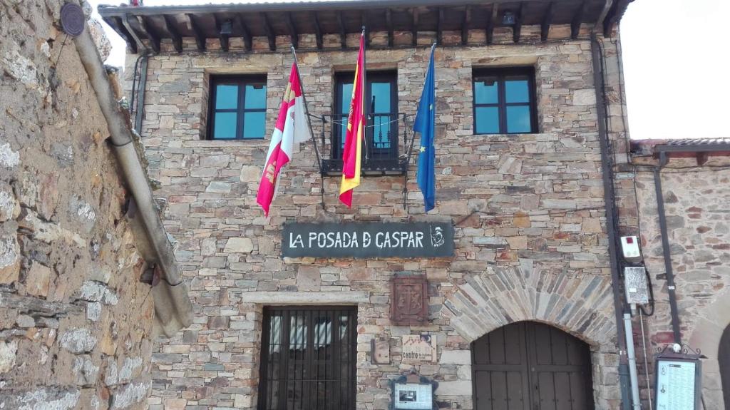 un edificio con banderas a un lado. en Posada De Gaspar, en Rabanal del Camino