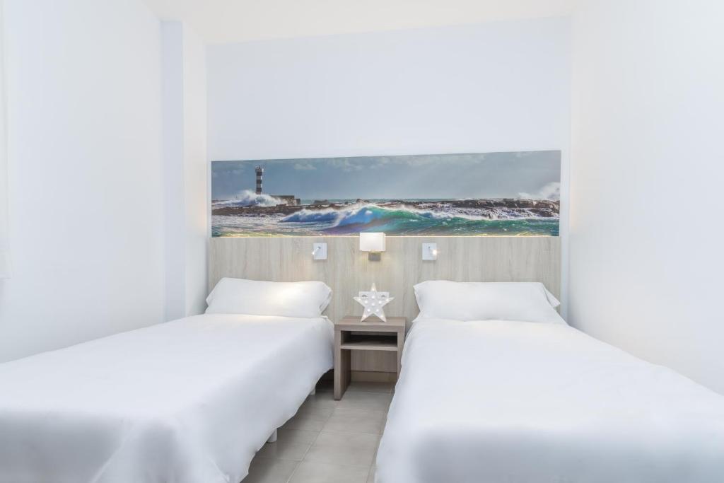 two beds in a room with a view of the ocean at Apartamentos Lago in Colonia Sant Jordi