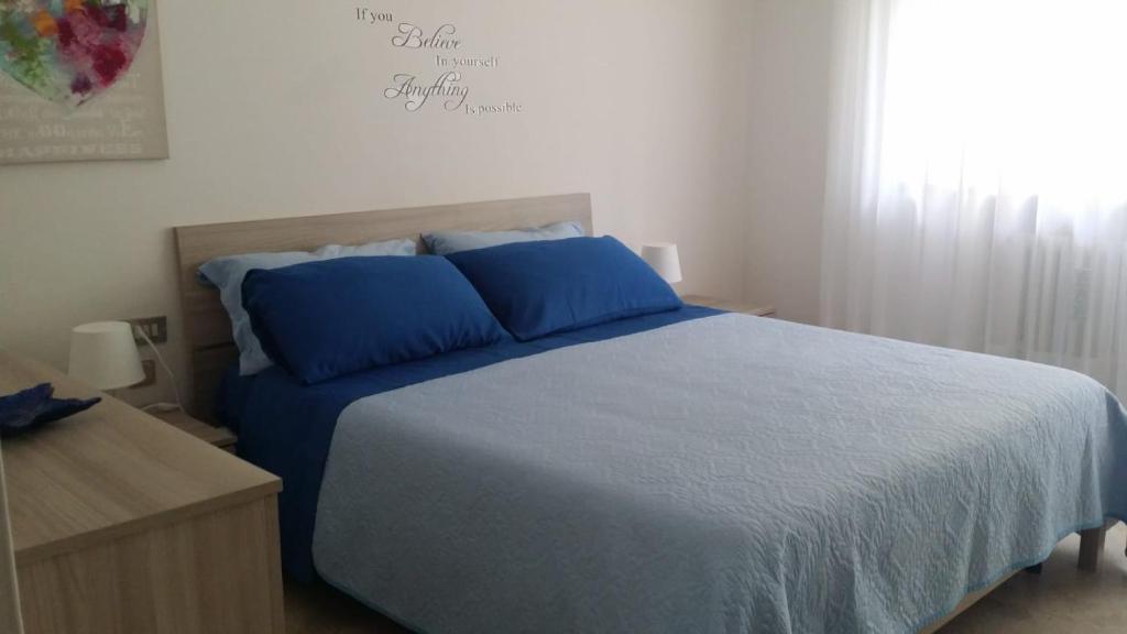 a bedroom with a bed with blue pillows and a window at la casa al mare in Pescara