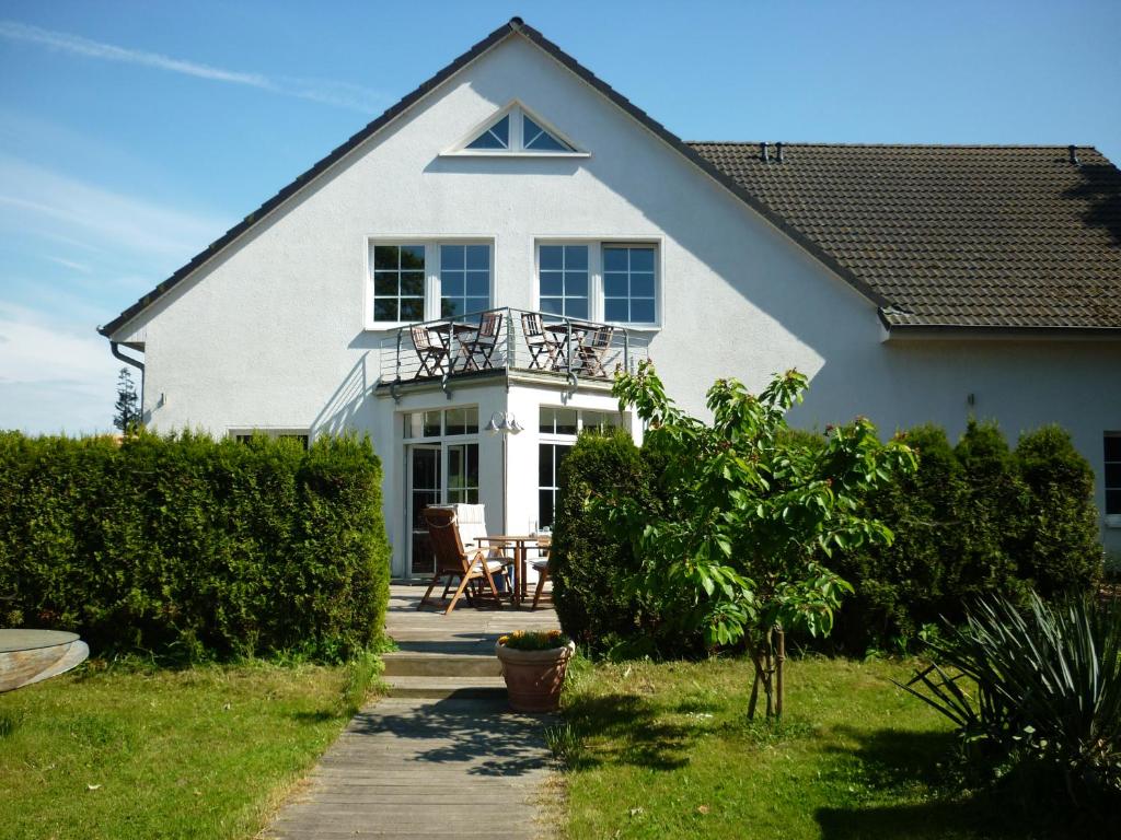 a white house with a balcony on top of it at Pension zum Leuchtturm in Bastorf