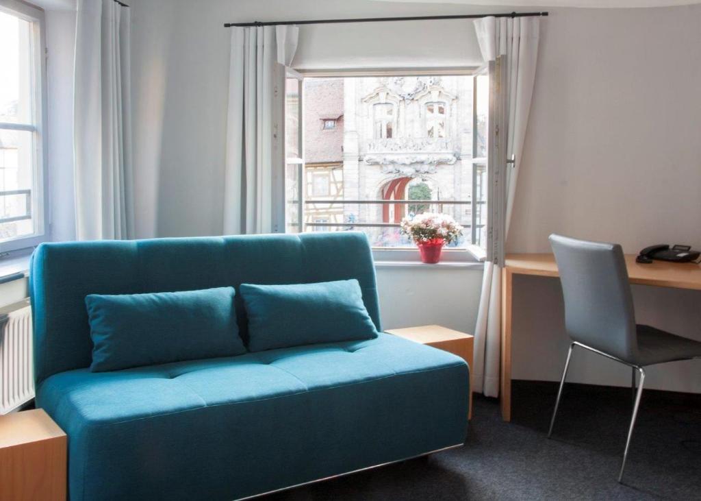 バンベルクにあるRathausschänkeの窓付きの客室で、青いソファが備わります。