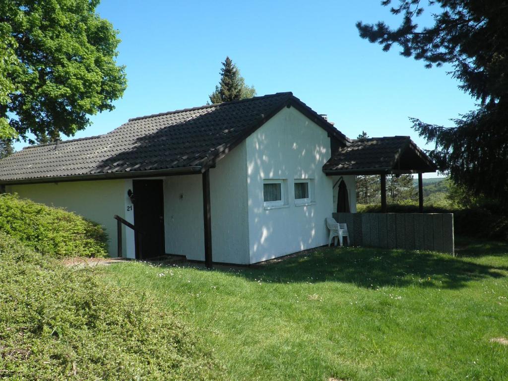 a white house with a chair in a yard at Blick in die Südeifel in Biersdorf am See