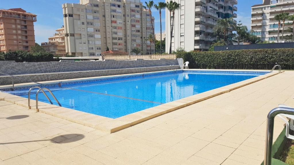 a large blue swimming pool with buildings in the background at ROMA XII - Apartamento Familiar in Playa de Gandia