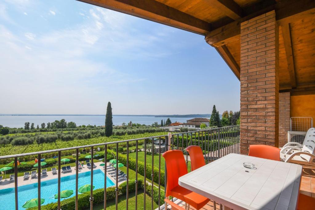 balcón con mesa, sillas y piscina en Residence Corte Ferrari -Ciao Vacanze- en Moniga