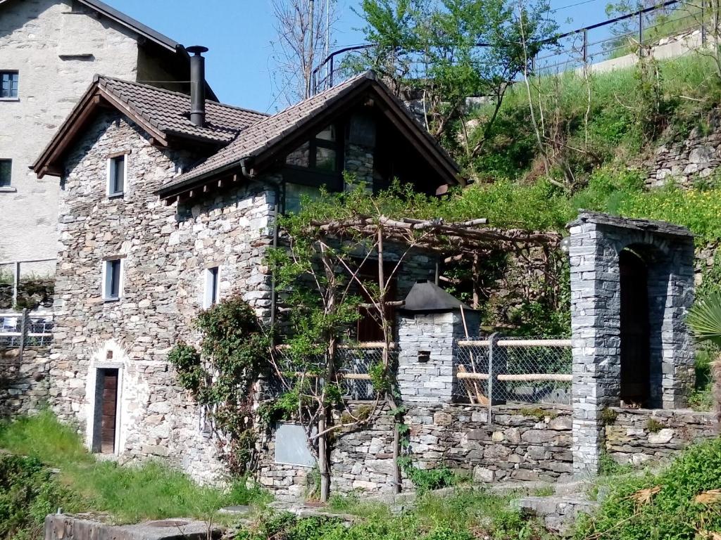 een oud stenen huis aan de zijkant van een heuvel bij Rustico "Casa di Sasso" in Intragna