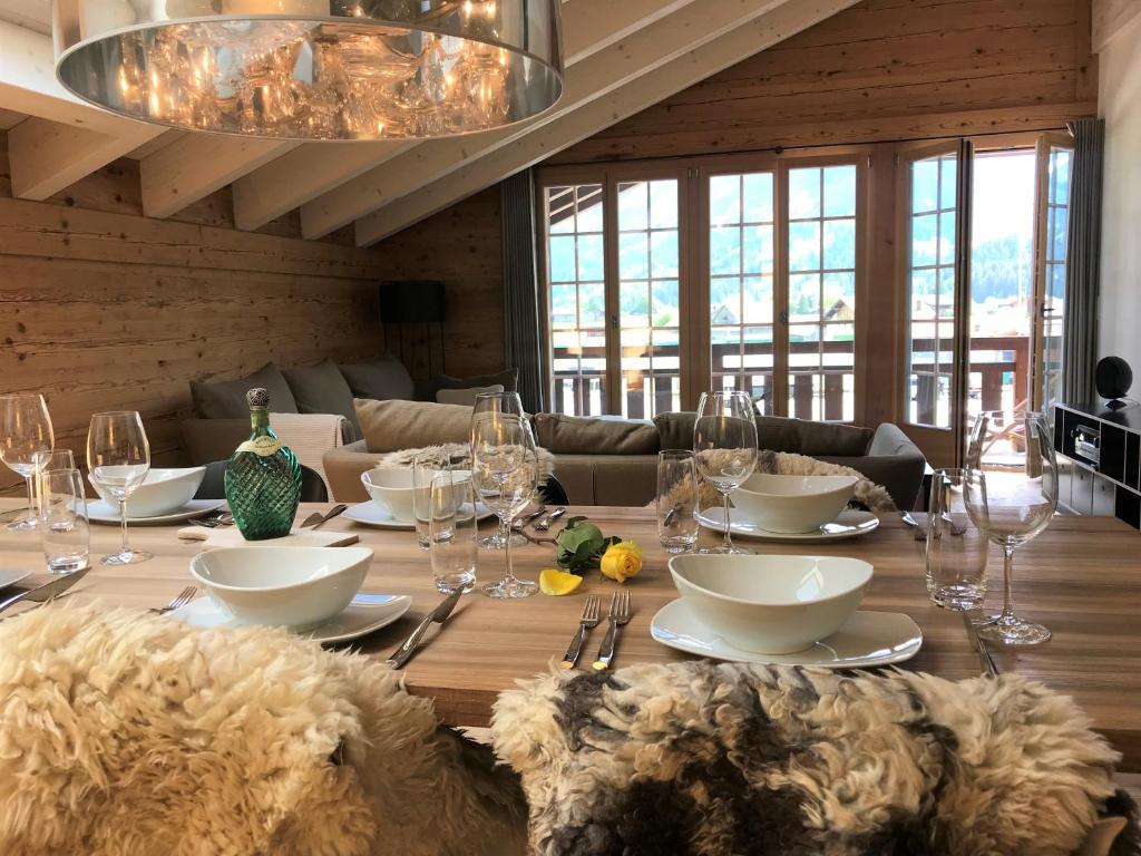 uma sala de jantar com uma mesa de madeira com copos em Chalet ELK Lenk em Lenk