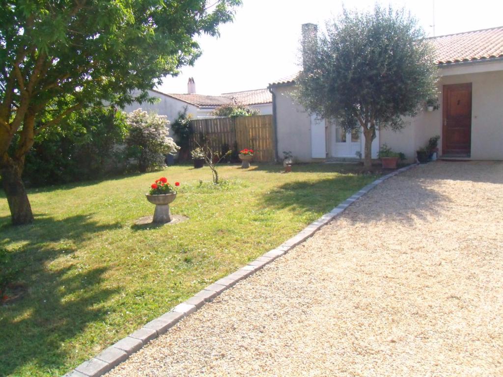 un cortile con una casa e un giardino con fiori rossi di L'oiseliere a Sainte-Marie-de-Ré