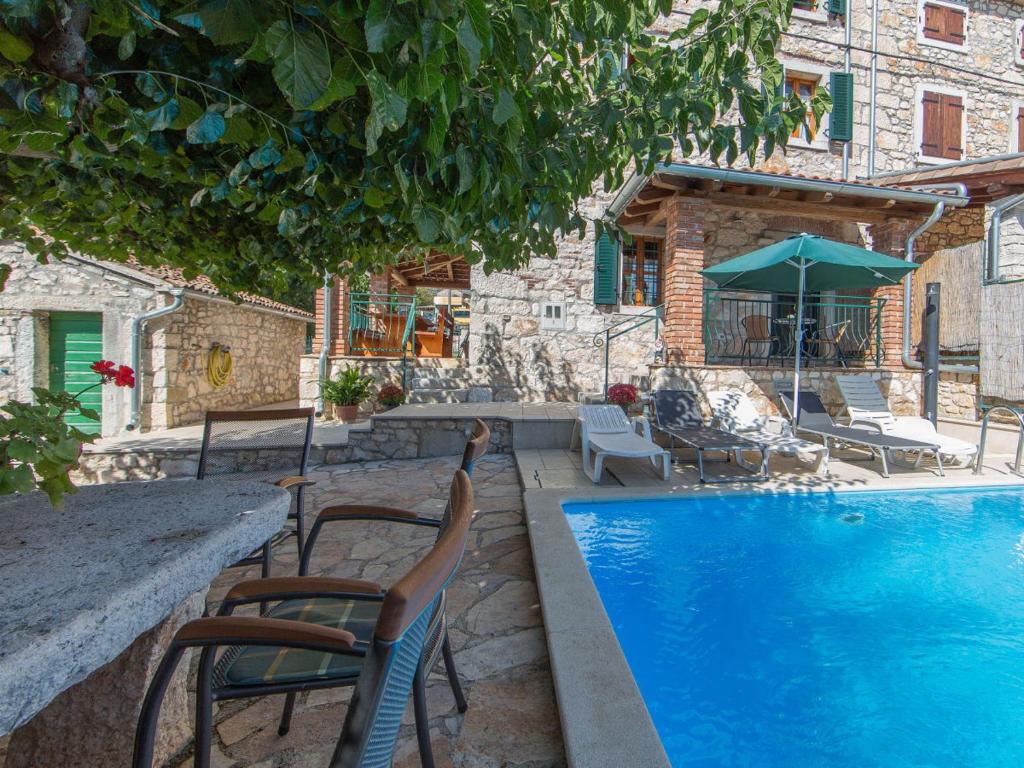 een zwembad met stoelen en een tafel en parasol bij Karmen 3 in Poreč