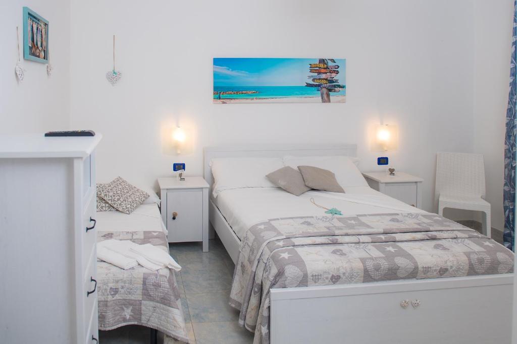 a white bedroom with two beds and two tables at Hotel San Giovanni in Polignano a Mare