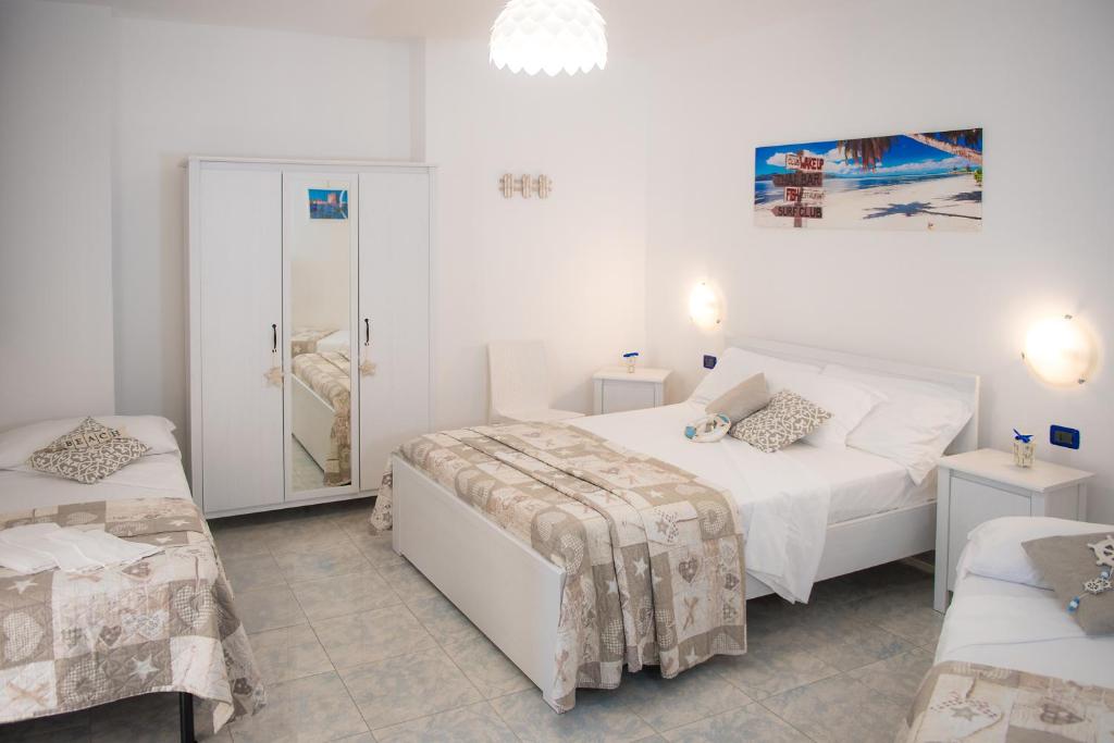a white bedroom with two beds and a mirror at Hotel San Giovanni in Polignano a Mare