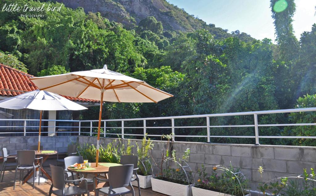un patio con mesas y sombrillas frente a una montaña en CabanaCopa Hostel, en Río de Janeiro