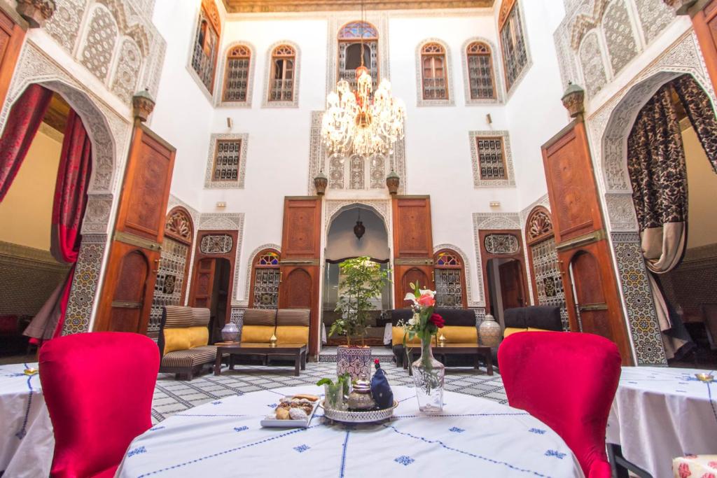 ein Esszimmer mit einem Tisch, Stühlen und einem Kronleuchter in der Unterkunft Riad Fez Yamanda in Fès