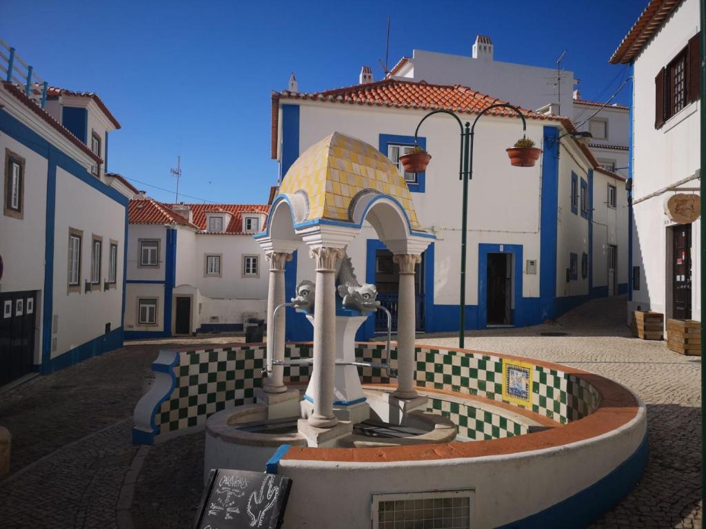 a fountain in the middle of a street with buildings at Refugio dos Lima in Ericeira