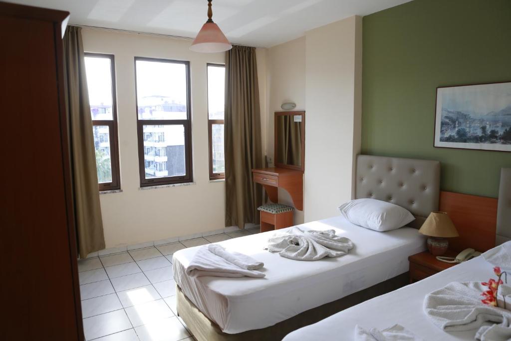 a hotel room with two beds and two windows at Maren Beach Apart Hotel in Alanya