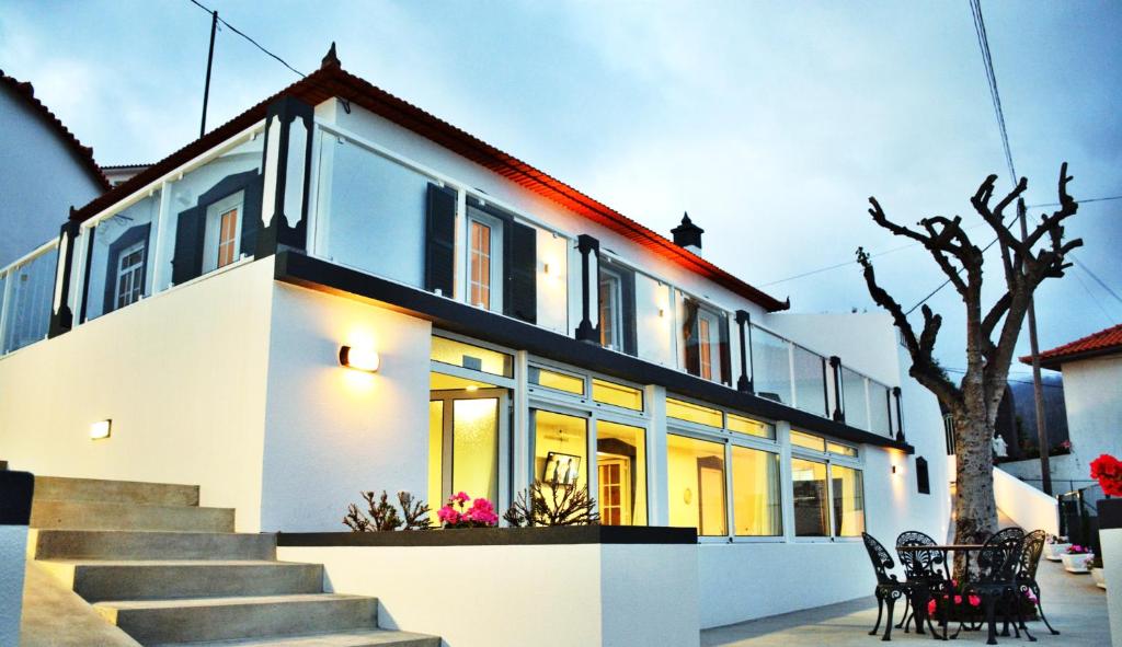 a white house with stairs and chairs in front of it at La Casa de la Abuela in Ponta do Sol