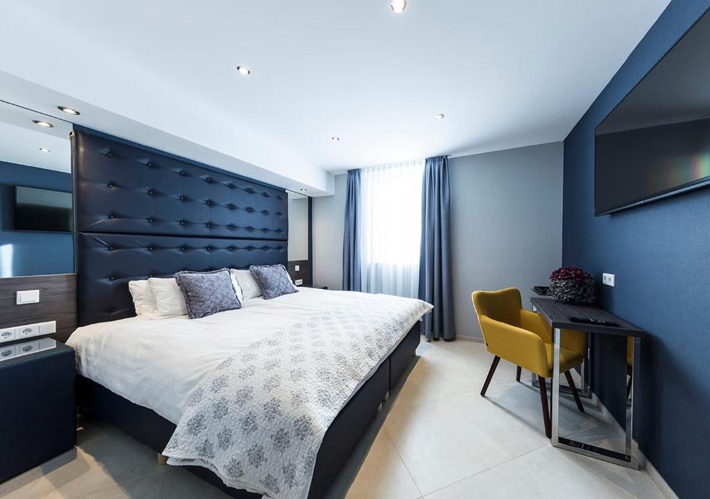 a bedroom with a large bed and a yellow chair at Hotel Tommasi in Mörfelden-Walldorf