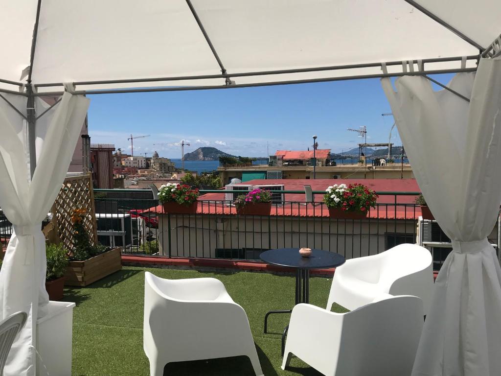 a patio with white chairs and a table and a tent at B&B FLAVIO in Pozzuoli