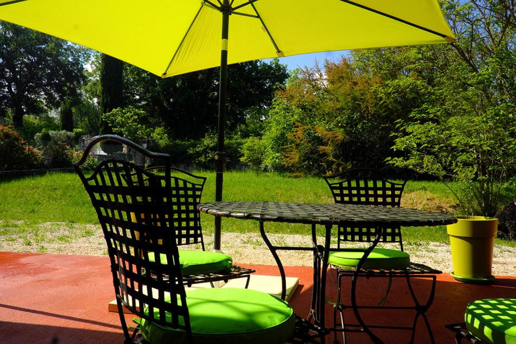een tafel en stoelen onder een gele paraplu bij Envies en Lubéron in Saignon
