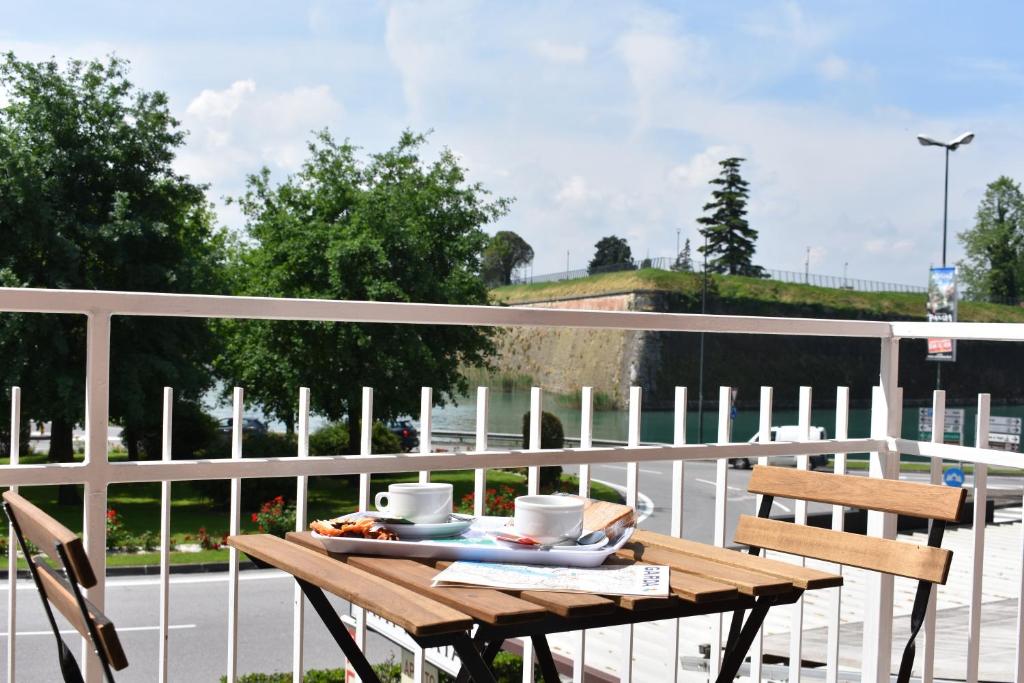 einen Holztisch mit Tassen und Tellern auf einem Balkon in der Unterkunft Lake moments in Peschiera del Garda