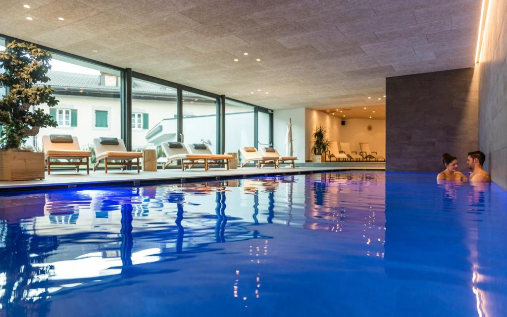 two people sitting in a swimming pool at Hotel Lener in Campo di Trens