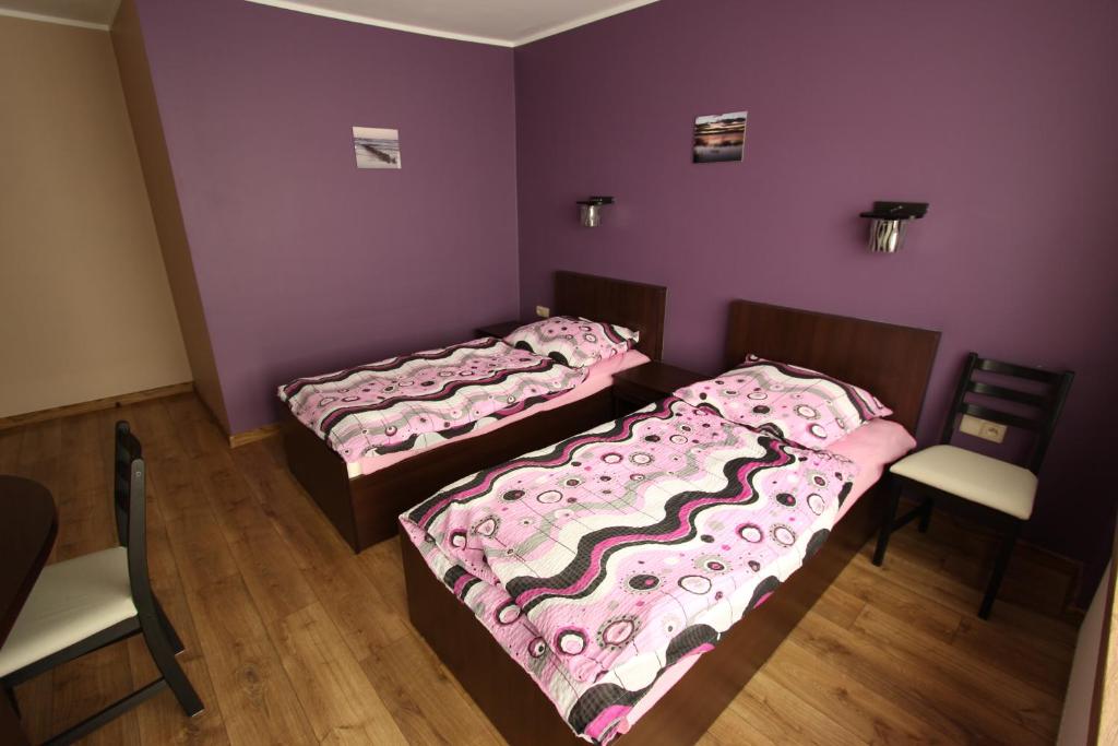 two beds in a room with purple walls and wooden floors at U ELŻBIETY in Łeba