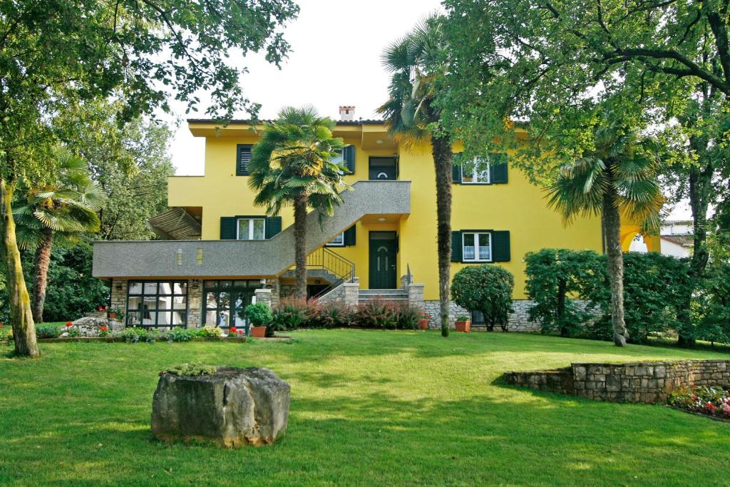 une maison jaune avec des palmiers dans la cour dans l'établissement Apartments Villa Concept, à Poreč